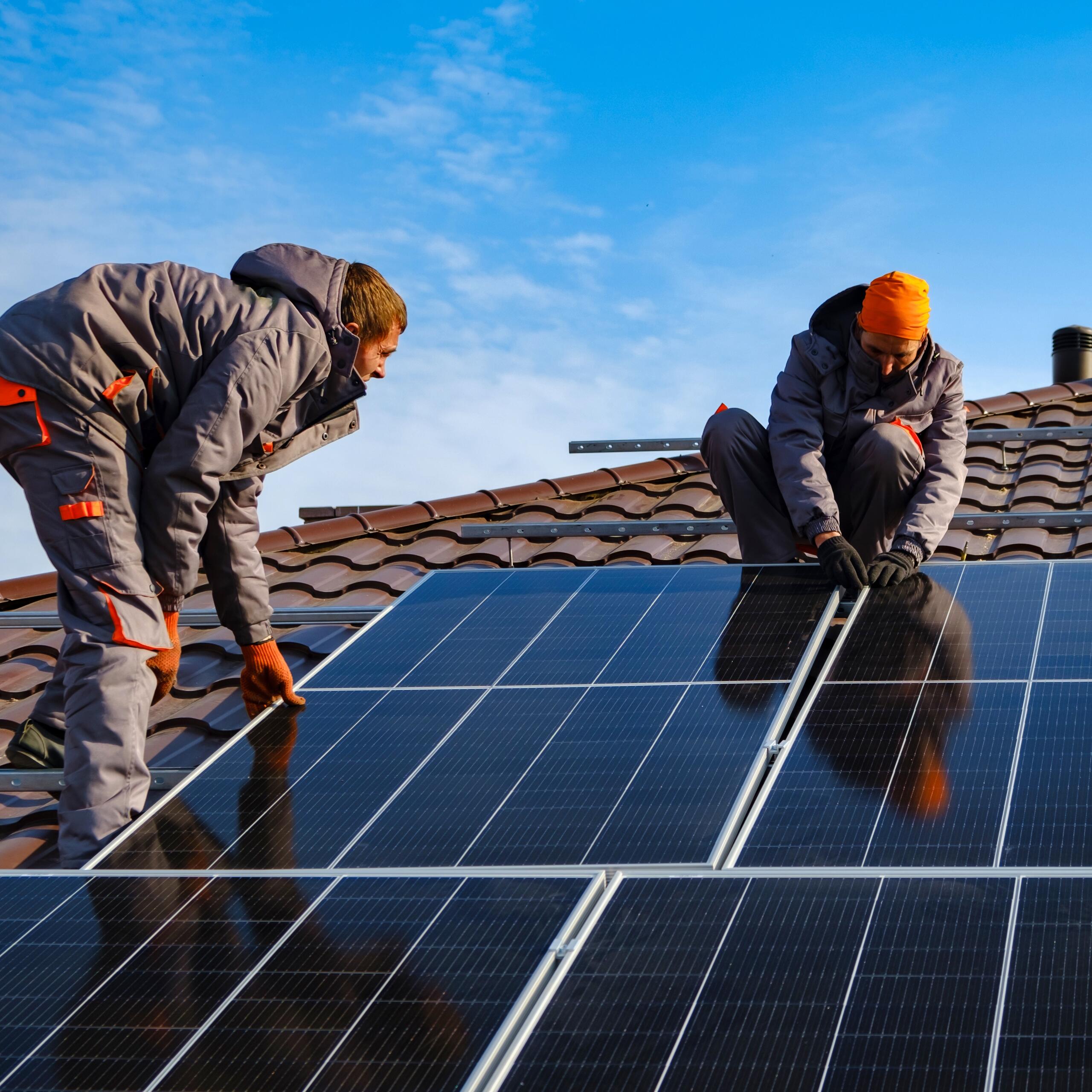 mannen op het dak leggen zonpanelen